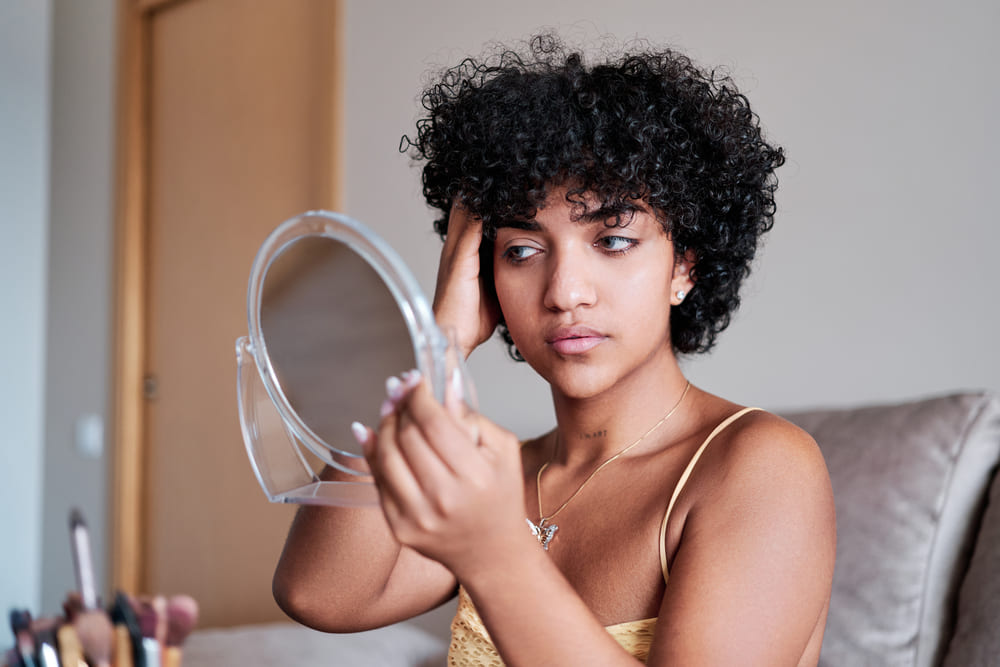 zdenerwowana kobieta patrząca na swoje włosy-patrząca w lustro