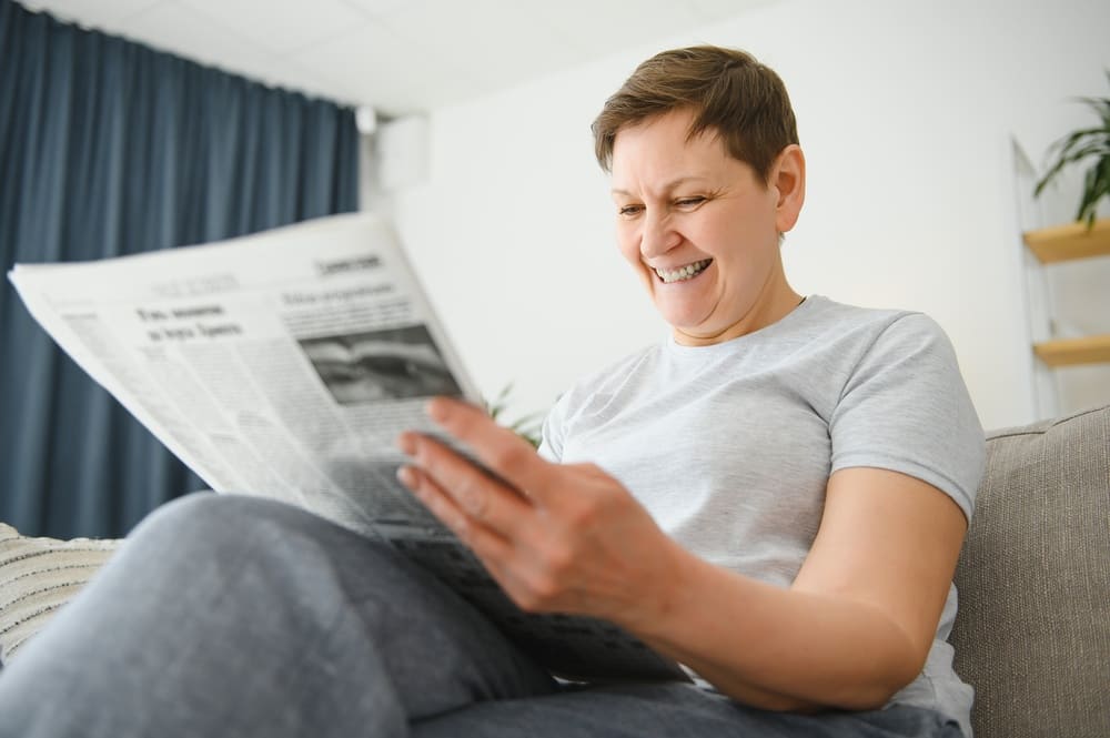 Kobieta czyta artykuł w gazecie na temat Ashwagandhy. 