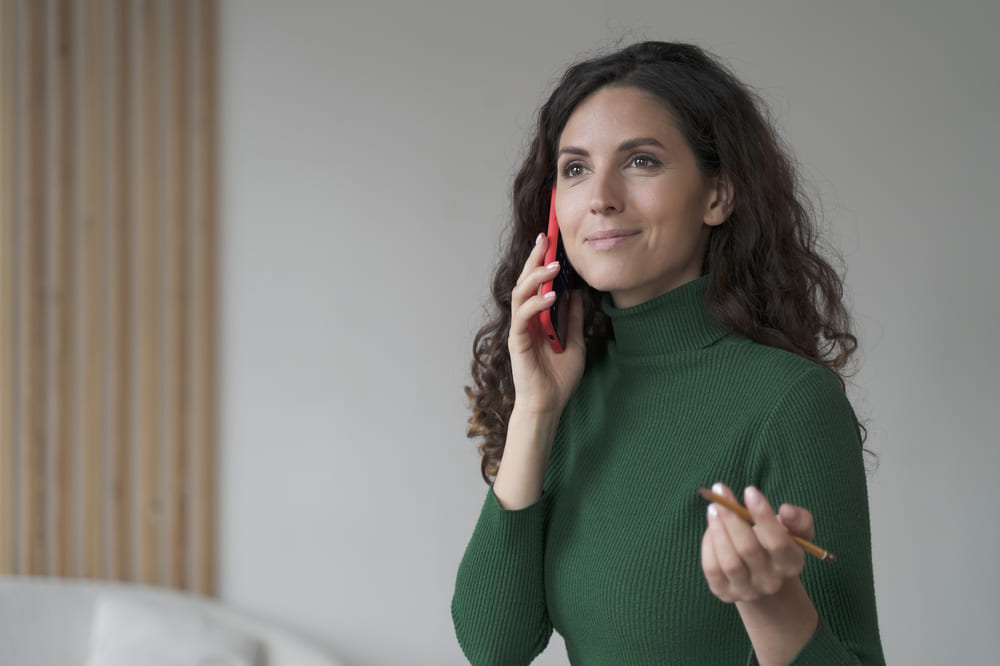 Kobieta rozmawia przez telefon - pyta się, czy dana dieta pudełkowa zawiera żeń-szeń. 